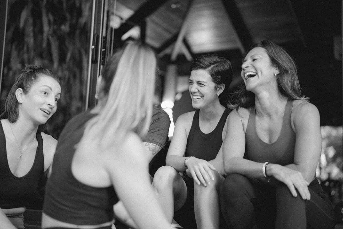 Black-and-white photo of women sitting together in the studio, laughing.
